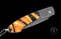 Luxury folding knife with orange and black striped handle, damascus steel blade, and braided lanyard, one of a kind, side view