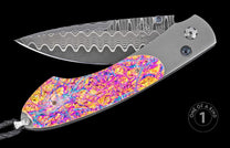 Damascus steel folding knife with vibrant mokume-gane handle, by W. H. Knives, featuring wave-pattern blade and sapphire accents, one-of-a-kind design, side view