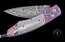 Damascus steel folding knife with purple and brown patterned handle, textured silver bolster, and braided lanyard, one of a kind