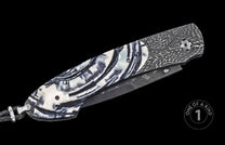 Luxury folding knife with black and white marbled handle, textured carbon fiber pattern, partially open blade, side view on black background