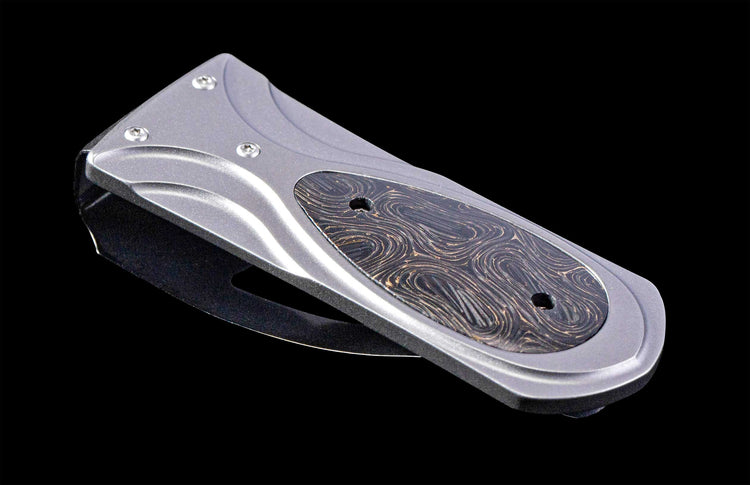 Gray metal money clip with a dark inlay featuring a swirling golden thread pattern, shown at an angle.