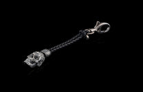 Black braided leather key chain by TOUCHSTONE with an ornate silver metal skull charm and a swivel clasp, displayed diagonally.