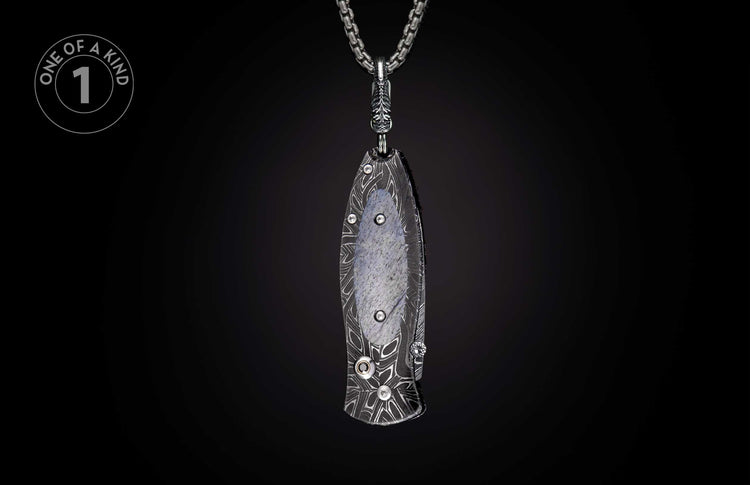 Dark patterned folding knife pendant featuring a gray stone inlay and crystal accents, suspended from a silver chain.