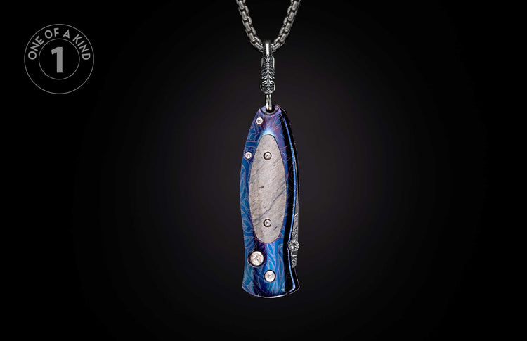 Pendant knife with iridescent blue-purple patterned handle and textured inlay, hanging from a silver chain.