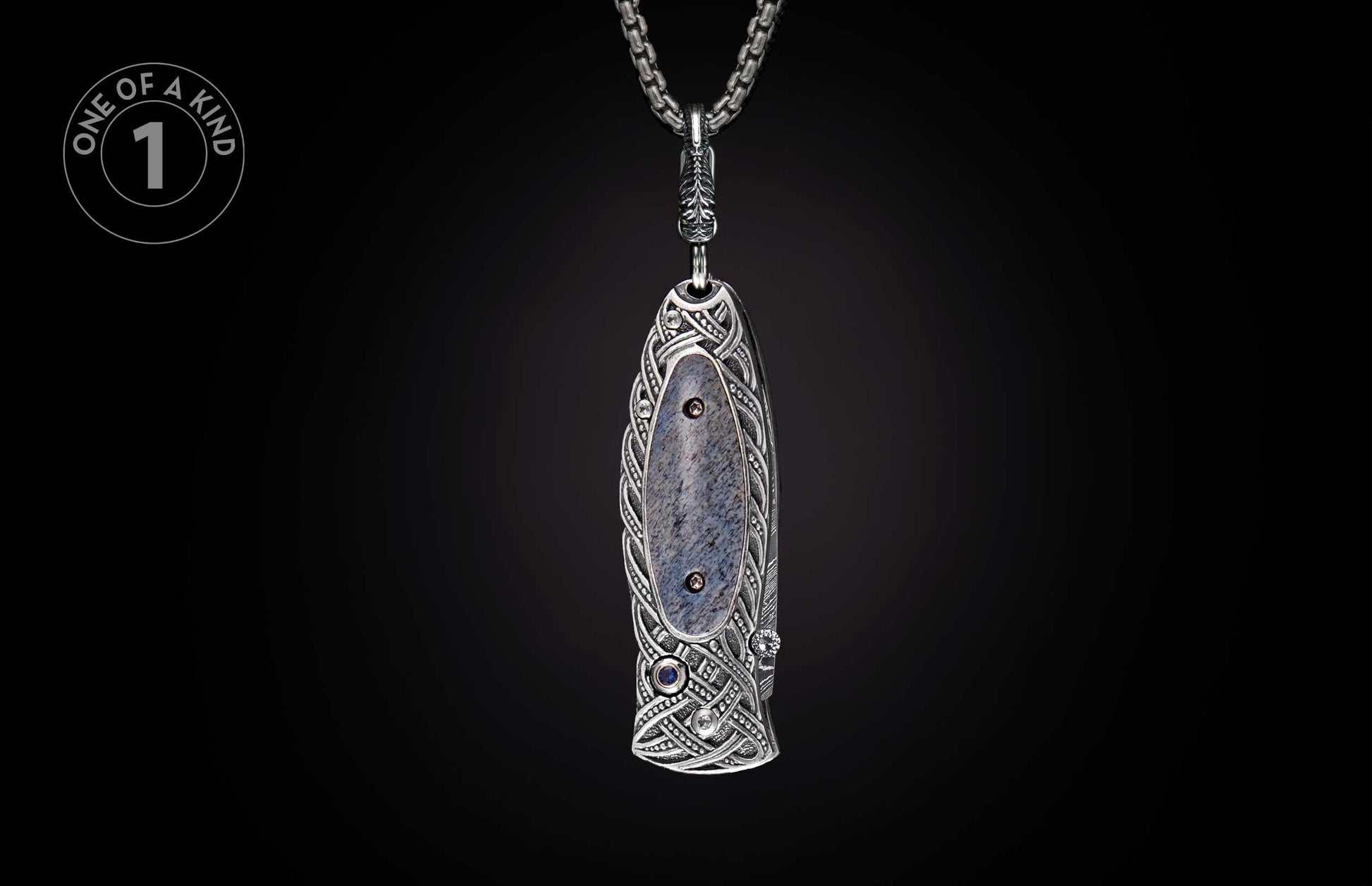 Ornate silver knife with intricate Celtic patterns, a grey-blue stone inlay, and sapphire accents, suspended by a chain.