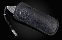 Handcrafted pocket knife from William Henry featuring a stainless steel frame hand-engraved with images of the Statue of Liberty and set with blue sapphires. The blade is hand-forged damascus steel.