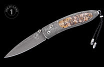 Decorative folding knife with a Damascus blade and handle, featuring a unique spotted stone inlay and a braided black leather lanyard.