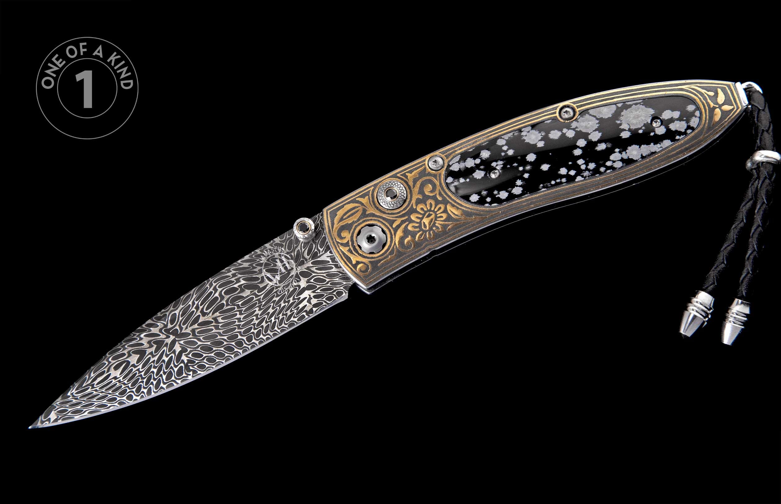 Ornate folding knife with a patterned Damascus blade, engraved gold handle, snowflake inlay, and black leather lanyard.
