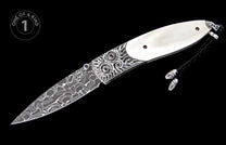 Folding knife with Damascus steel blade, ornate silver bolsters featuring blue gemstones, white handle scales, and a black braided lanyard.