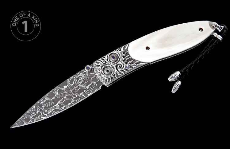 Folding knife with Damascus steel blade, ornate silver bolsters featuring blue gemstones, white handle scales, and a black braided lanyard.