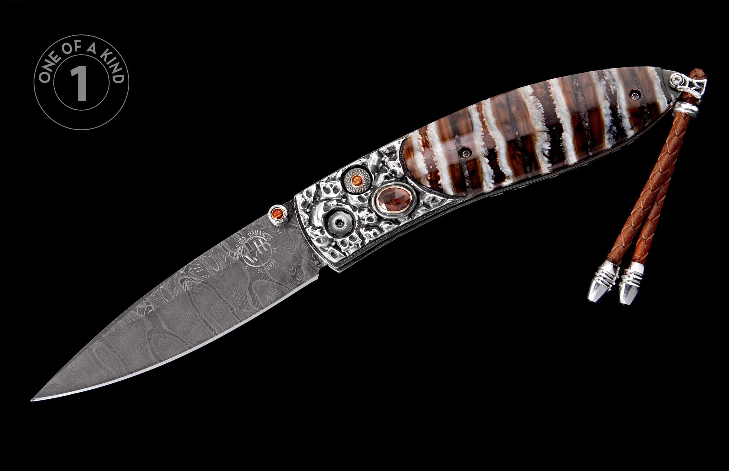 Damascus steel folding knife with ornate silver bolsters, orange gemstones, and a striped bone handle, featuring a brown leather lanyard.