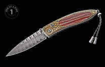 Folding knife with a damascus steel blade, gold scrollwork, reddish-brown striped handle inlay, and a black braided leather lanyard.