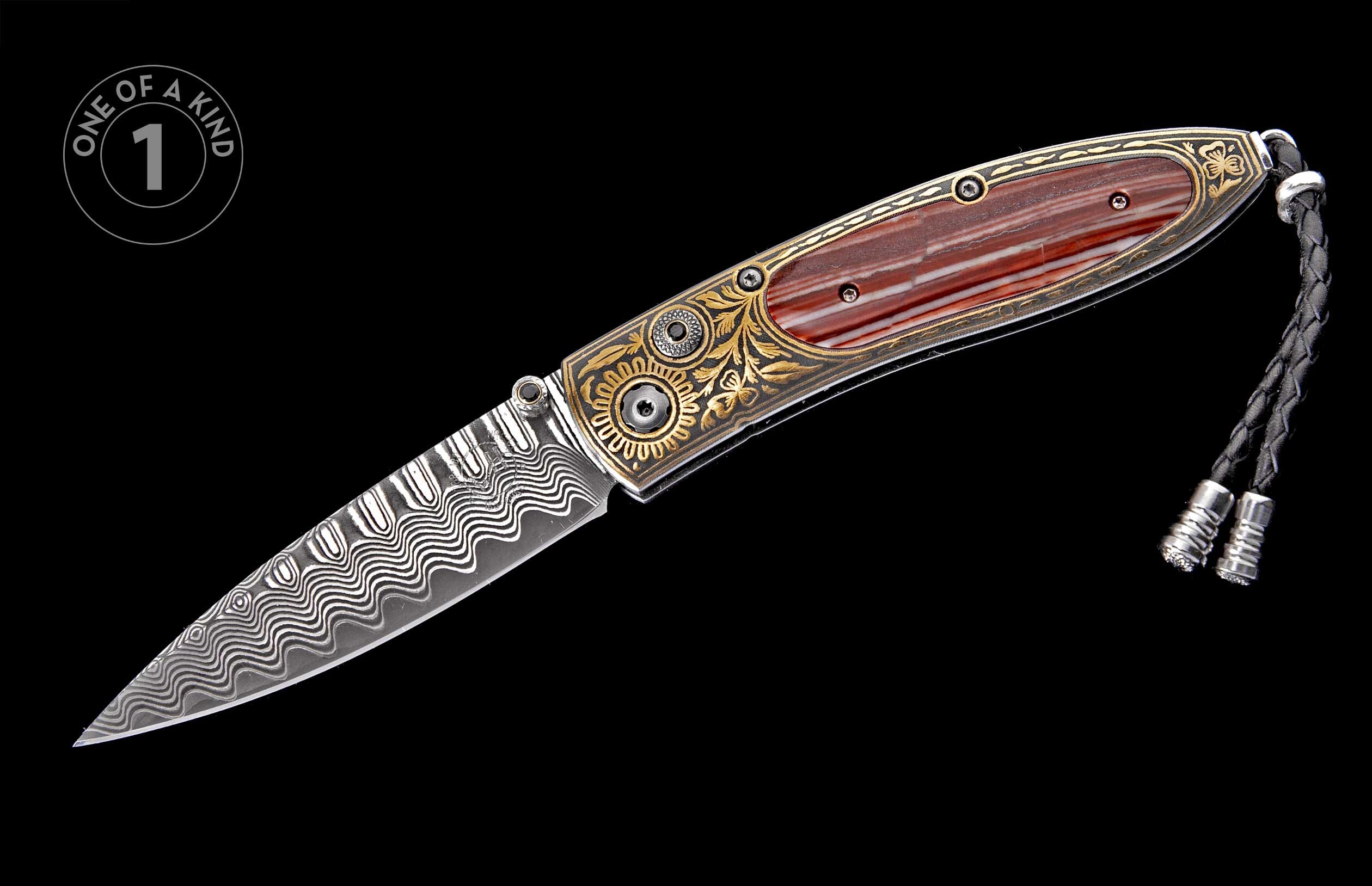 Folding knife with a damascus steel blade, gold scrollwork, reddish-brown striped handle inlay, and a black braided leather lanyard.