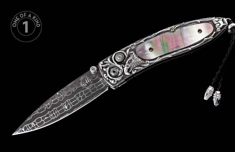 Ornate silver folding knife with a Damascus blade, iridescent mother-of-pearl handle, wolf carving, blue gemstones, and a braided black cord.