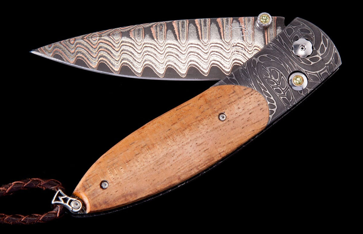 Folding knife with a Damascus steel blade and wooden handle by Hildgund Exclusive, featuring a wavy blade pattern and ornate dark metal with yellow gem details.