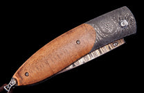 Light brown wooden handled folding knife by Hildgund, featuring intricate dark Damascus steel patterns and a textured metal spine.