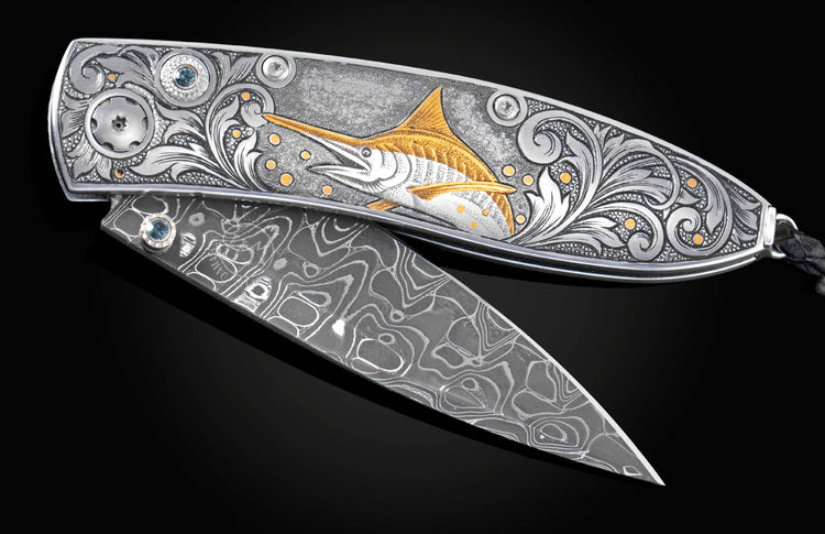 Handcrafted pocket knife from William Henry features a hand-engraved image of a Marlin with 24K gold inlays and set with dark Kashmir blue topaz and a hand forged Damascus steel blade.