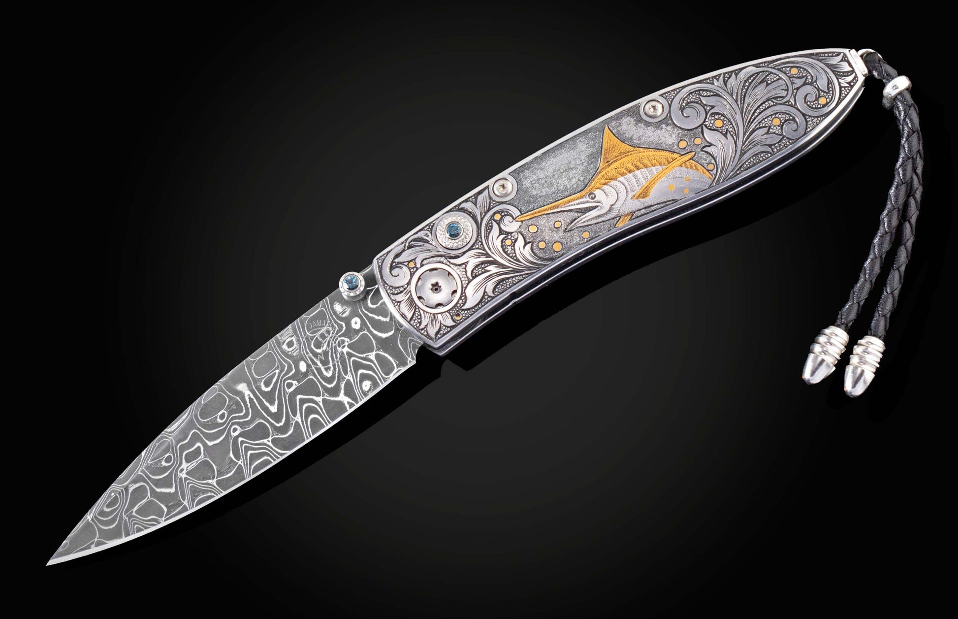 Handcrafted pocket knife from William Henry features a hand-engraved image of a Marlin with 24K gold inlays and set with dark Kashmir blue topaz and a hand forged Damascus steel blade.