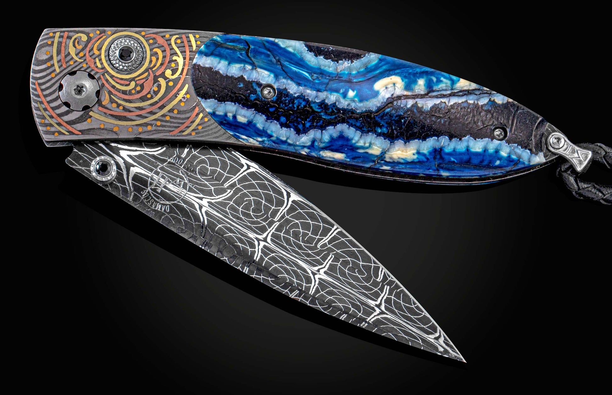 Handcrafted knife from William Henry featuring a hand-forged frame by Chad Nichols, hand-engraved inlays of gold and copper by Tyler Prince, spinel gemstones, fossil woolly mammoth tooth scales, and a hand-forged Damascus steel blade by Larry Donnelly
