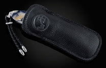 Handcrafted pocket knife from William Henry features a hand-engraved skull and intricate designs with 24K gold inlaid with fossil Woolly Mammoth tusk and set with spinel gemstones. The blade is damascus steel.