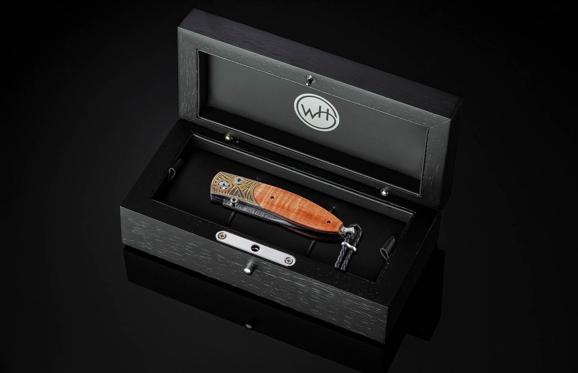 Handcrafted pocket knife with Damascus steel blade and scales featuring curly koa wood and 24K gold koftgari. Displayed in a wooden display case.
