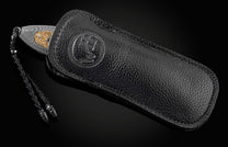 Handmade pocket knife from William Henry features a frame in hand-forged Damascus inlaid with 18K gold scales embedded with white diamonds by Alex Sepkus. The blade is hand forged Damascus steel.