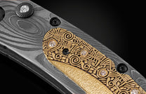 Handmade pocket knife from William Henry features a frame in hand-forged Damascus inlaid with 18K gold scales embedded with white diamonds by Alex Sepkus. The blade is hand forged Damascus steel.