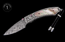 Ornate folding knife with silver-toned metal, mother-of-pearl, purple gemstones, a Damascus steel blade, braided leather lanyard, and "ONE OF A KIND" label.