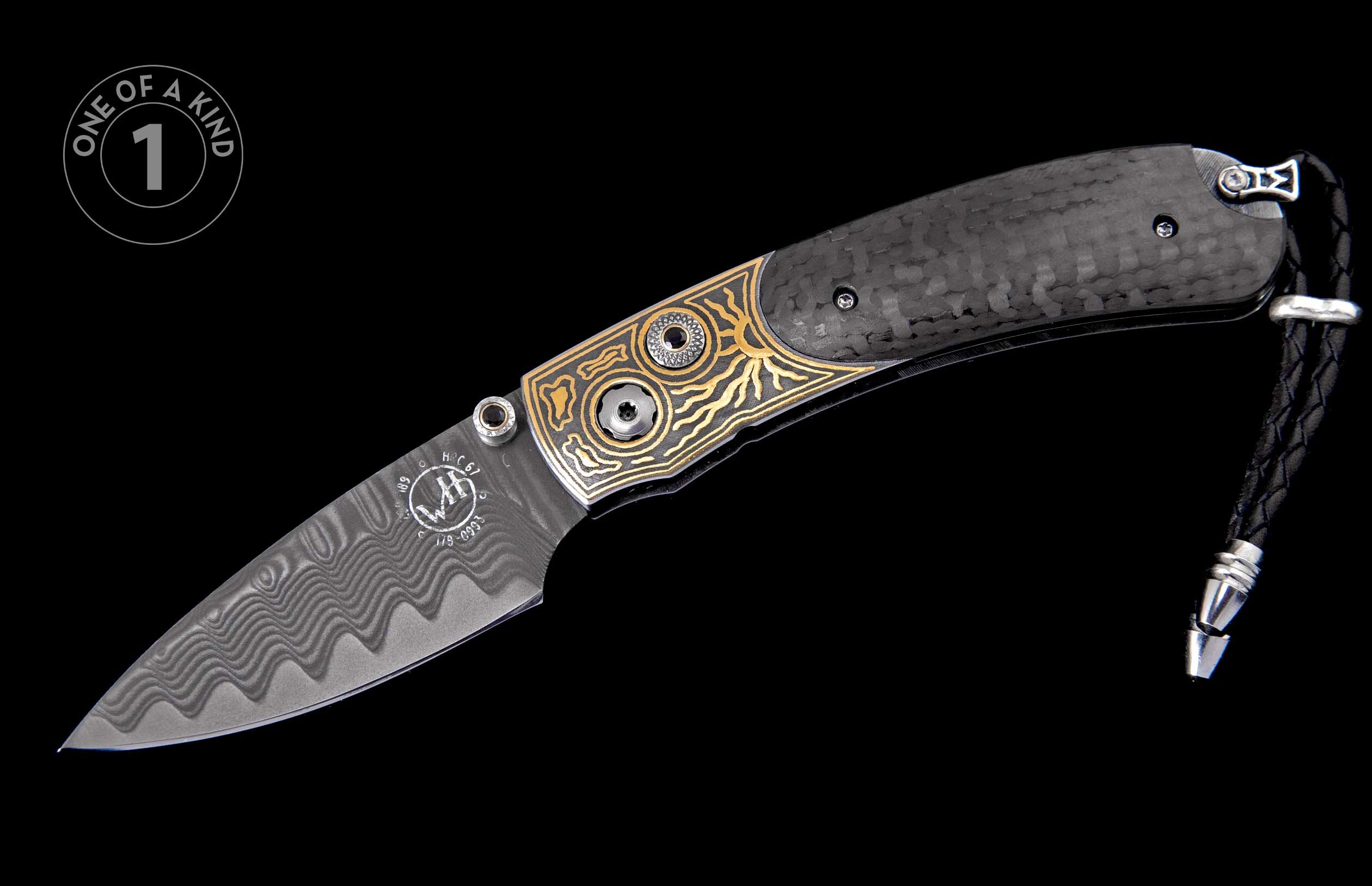 Custom folding knife featuring a Damascus steel blade, black carbon fiber handle with golden sun-motif inlay, and a braided leather lanyard.