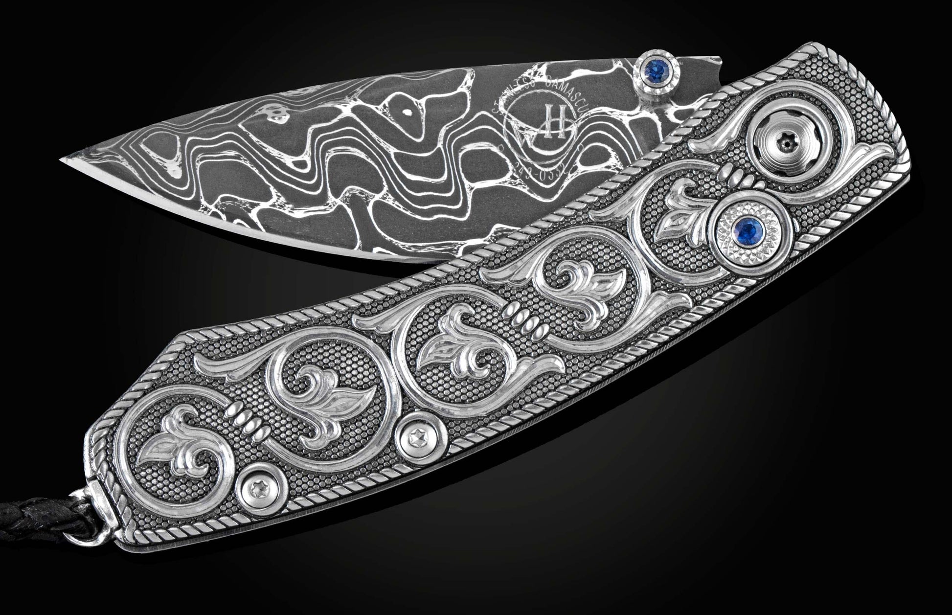 Handcrafted pocket knife from William Henry features hand and laser engraved handles set with sapphire gemstones and a blade of hand-forged Damascus steel.