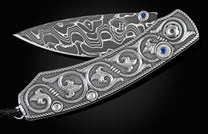 Handcrafted pocket knife from William Henry features hand and laser engraved handles set with sapphire gemstones and a blade of hand-forged Damascus steel.