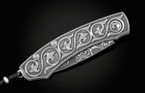 Handcrafted pocket knife from William Henry features hand and laser engraved handles set with sapphire gemstones and a blade of hand-forged Damascus steel.
