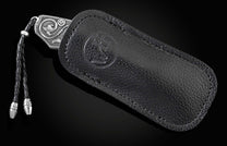 Handcrafted pocket knife from William Henry features hand and laser engraved handles set with sapphire gemstones and a blade of hand-forged Damascus steel.