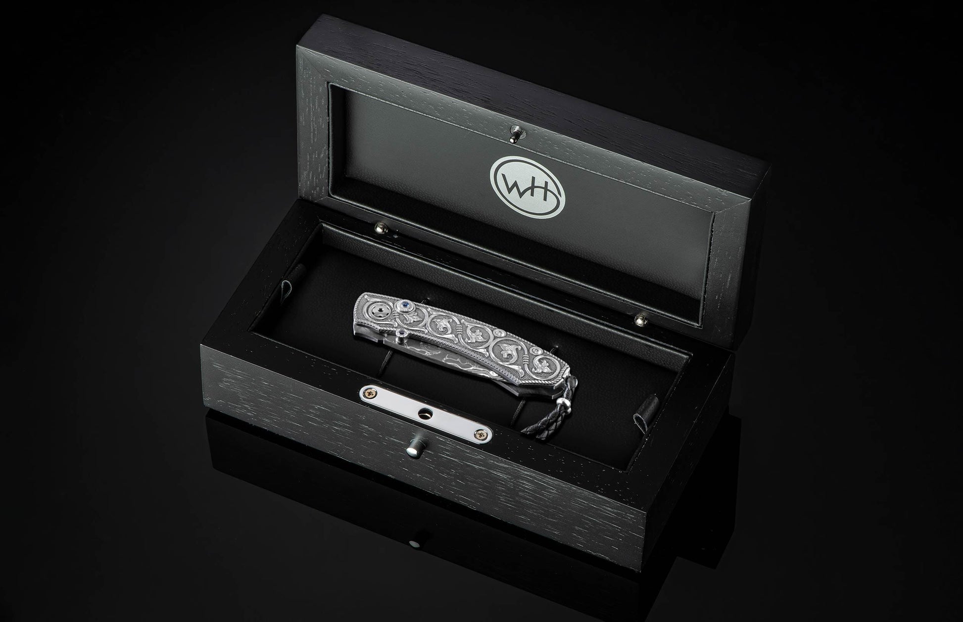 Handcrafted pocket knife from William Henry features hand and laser engraved handles set with sapphire gemstones and a blade of hand-forged Damascus steel.