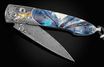 Handcrafted William Henry knife with hand-engraved frame featuring hummingbirds in 24K & 18K green gold, silver, and copper by Thierry Duguet, inlaid with fossil woolly mammoth tusk, spinel gemstones and a hand-forged damascus steel blade by Chad Nichols