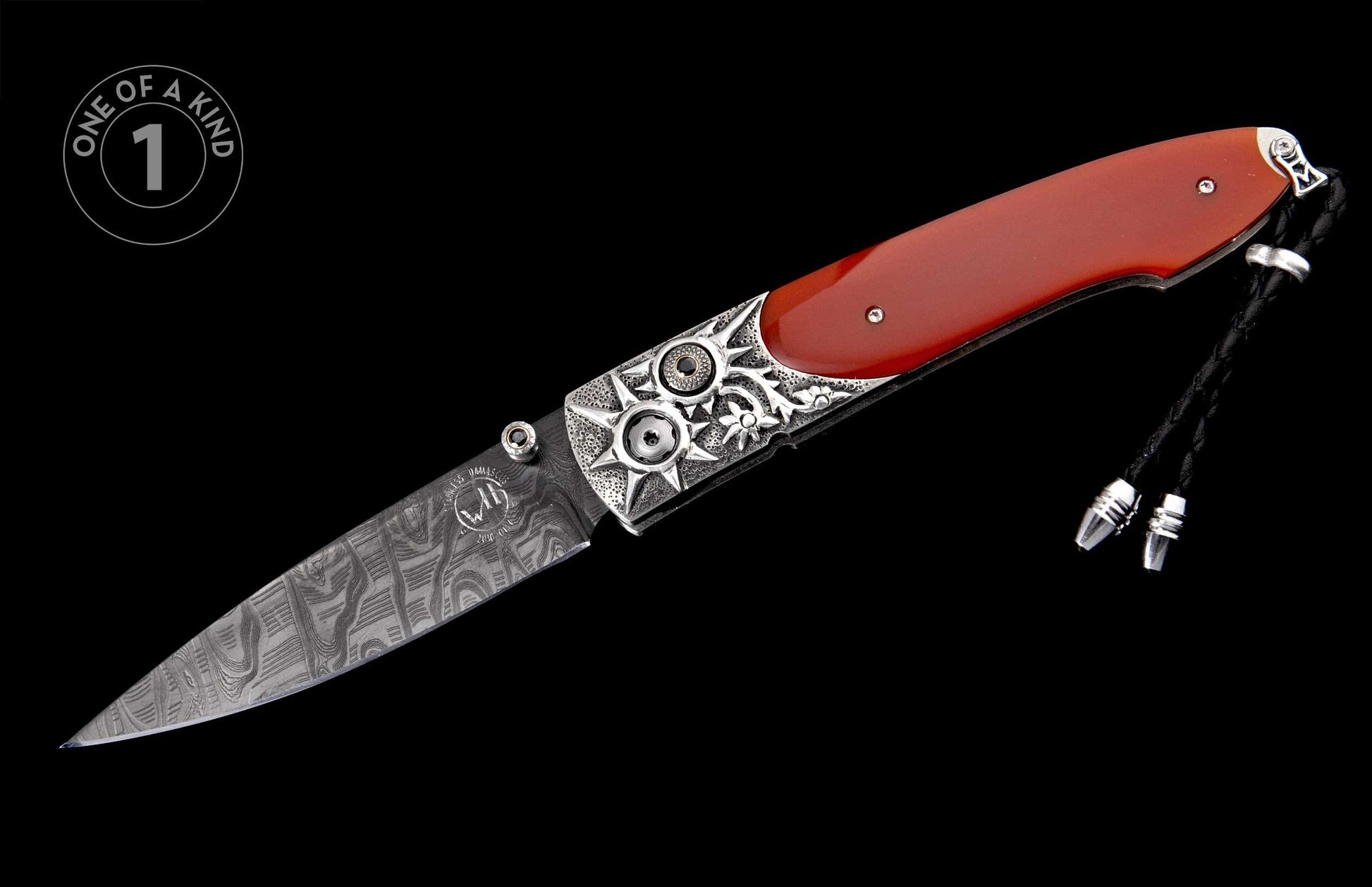 Folding knife with red handle, patterned Damascus blade, ornate silver bolsters featuring starburst designs, and a black braided lanyard.
