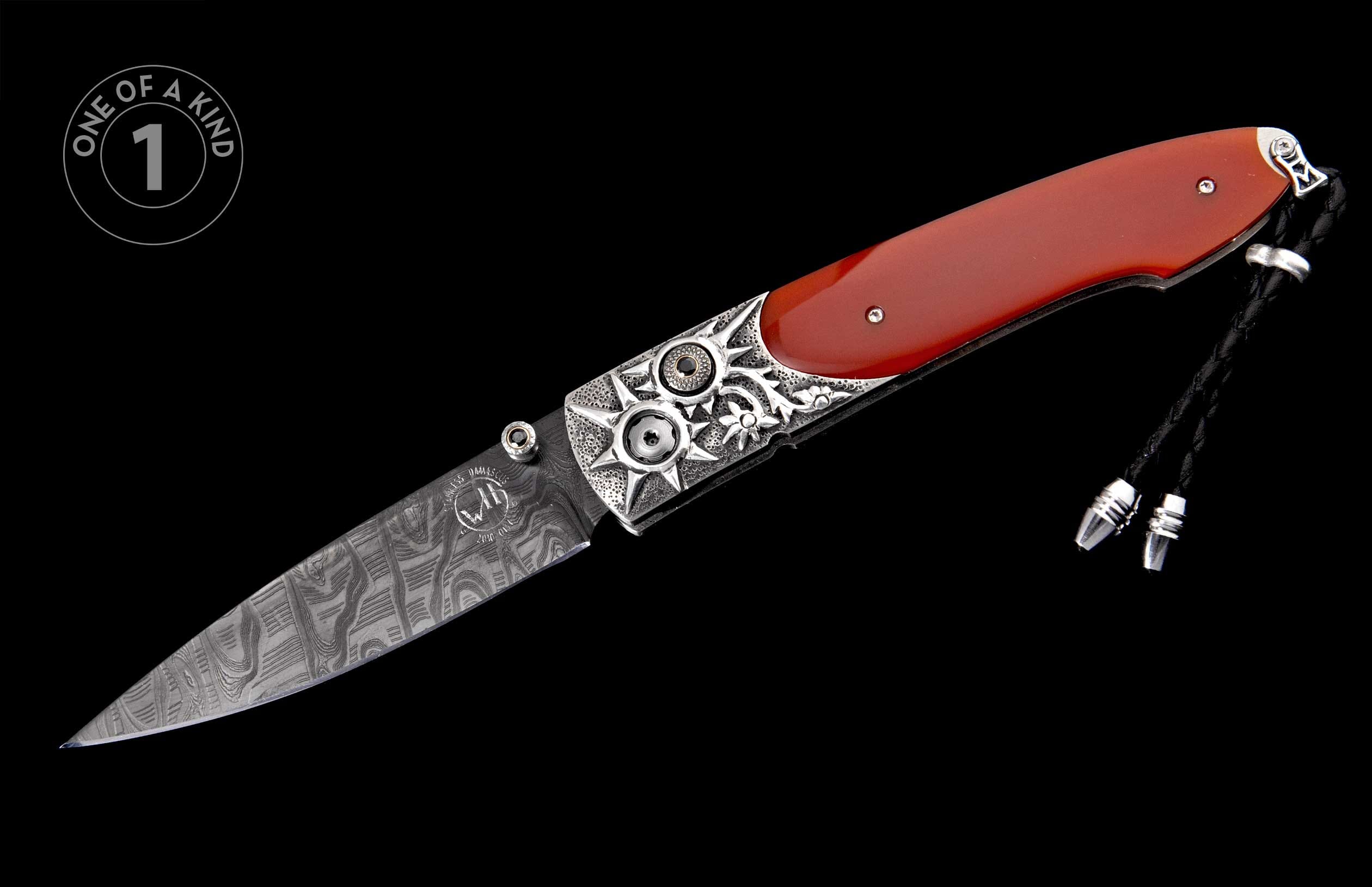 Folding knife with red handle, patterned Damascus blade, ornate silver bolsters featuring starburst designs, and a black braided lanyard.