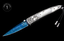 Blue meteorite Damascus knife with ornate silver handle, white mother-of-pearl inserts, black braided lanyard, and 'ONE OF A KIND 1' badge.