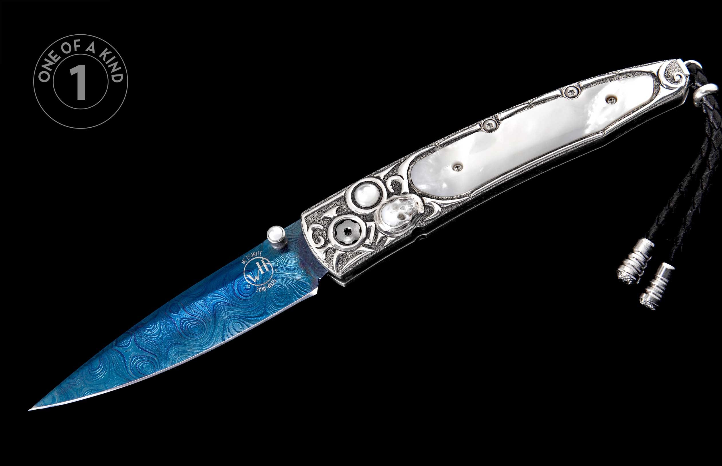 Blue meteorite Damascus knife with ornate silver handle, white mother-of-pearl inserts, black braided lanyard, and 'ONE OF A KIND 1' badge.