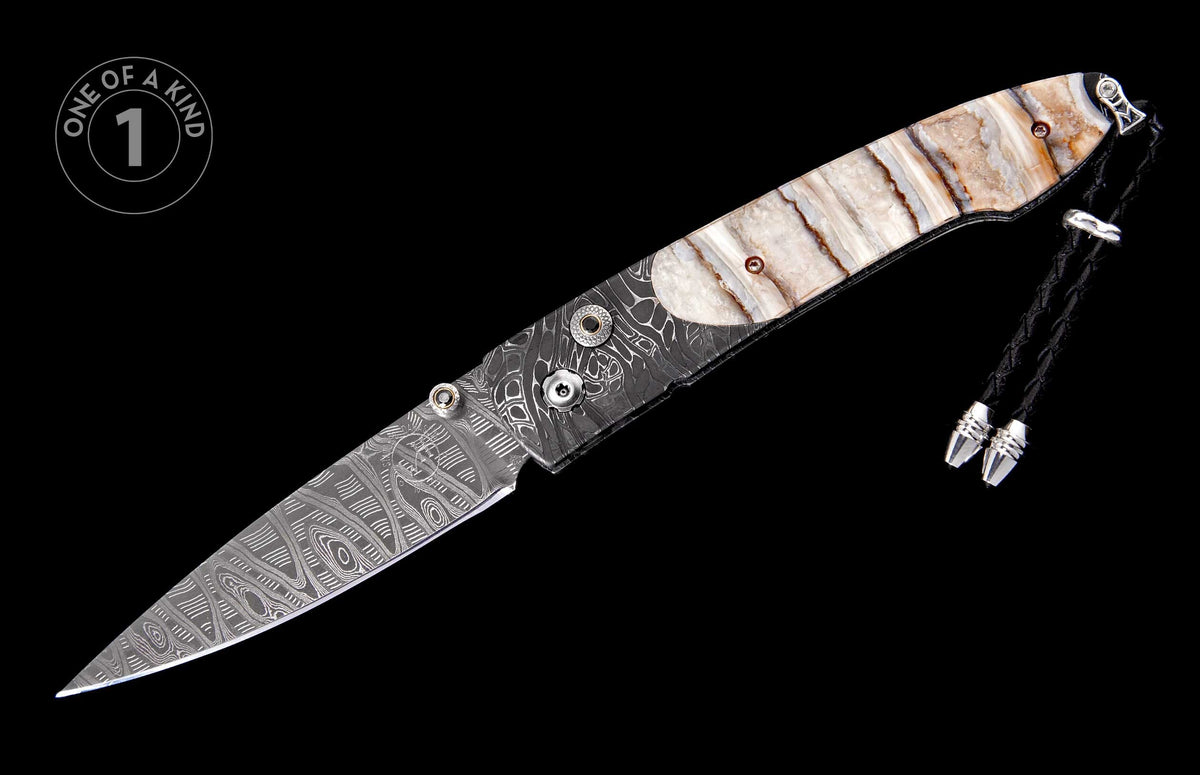 Damascus steel folding knife with a banded polished stone handle and black braided leather lanyard.