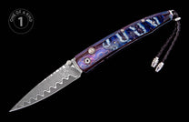 Folding knife with a wavy Damascus steel blade and a blue-purple handle featuring a crackle pattern with lighter marbling and a braided black lanyard.