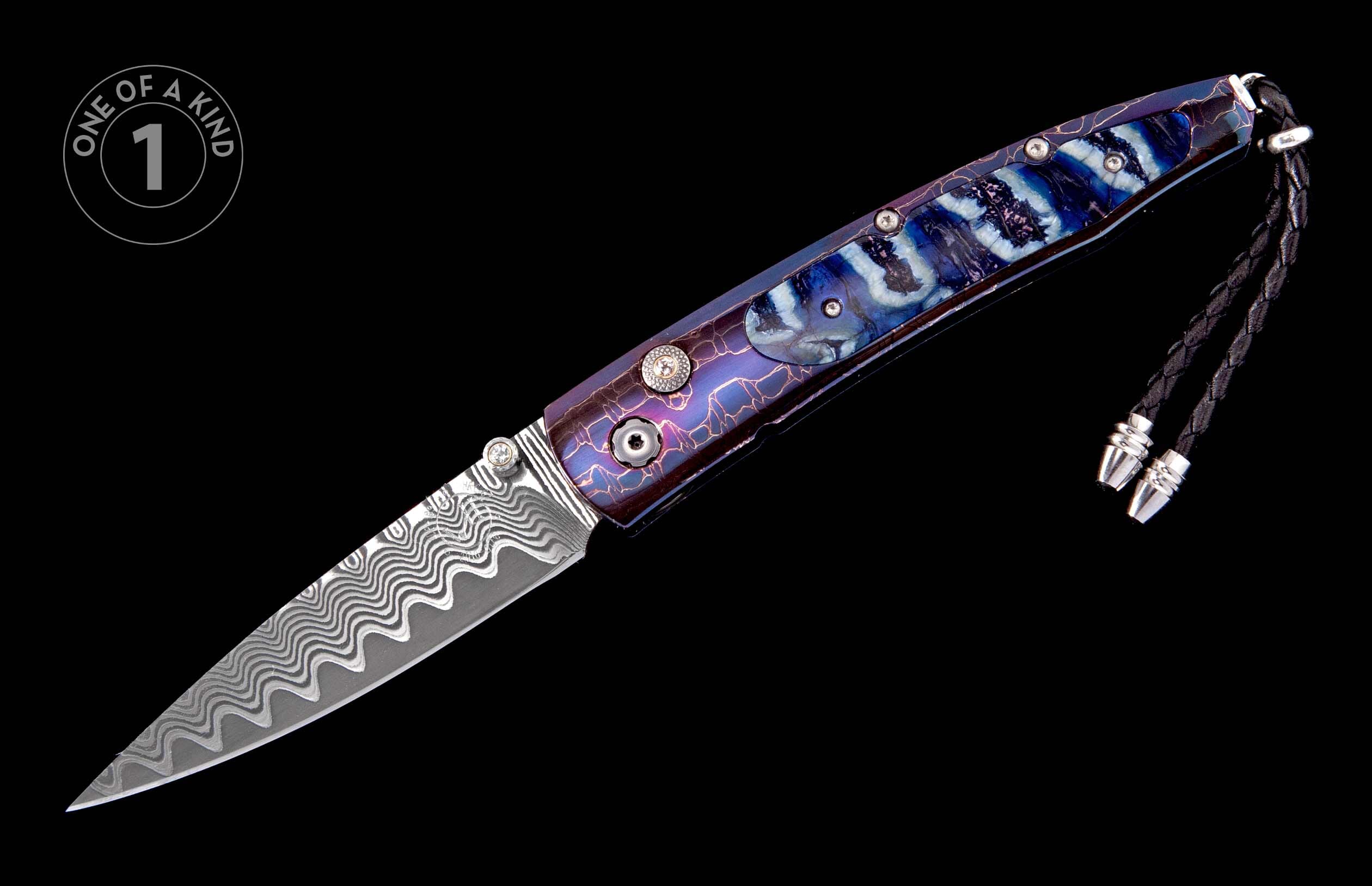 Folding knife with a wavy Damascus steel blade and a blue-purple handle featuring a crackle pattern with lighter marbling and a braided black lanyard.