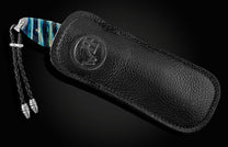 Handcrafted pocket knife from William Henry featuring a laser engraved stainless frame and scales of blue fossil Woolly Mammoth tooth. The blade is hand-forged damascus steel and the button lock and the thumb stud are set with spinel gemstones.