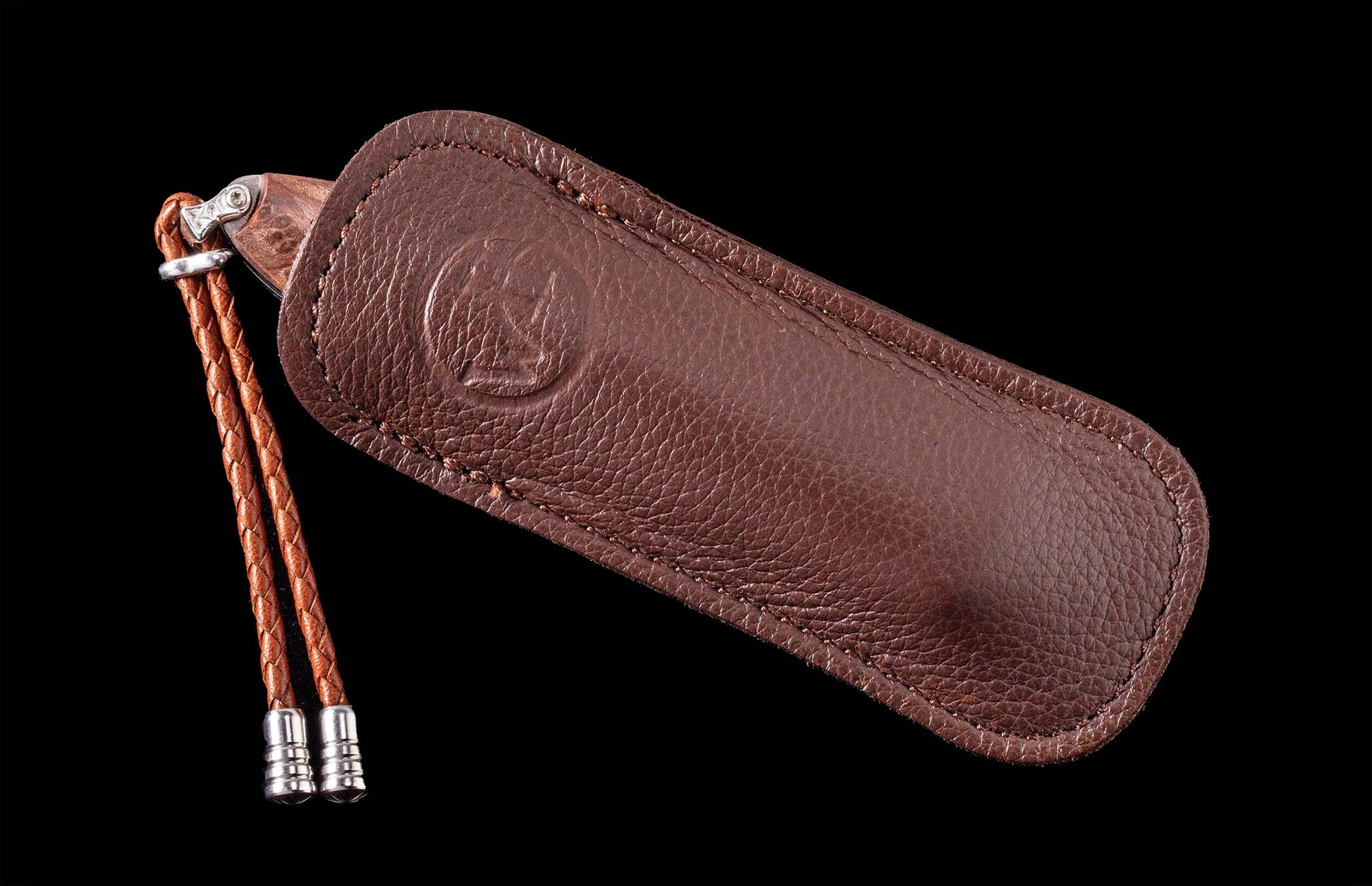 Brown leather-sheathed knife with a wooden handle, an embossed logo on the sheath, and a braided leather lanyard with silver tips.