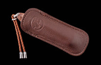Brown leather-sheathed knife with a wooden handle, an embossed logo on the sheath, and a braided leather lanyard with silver tips.