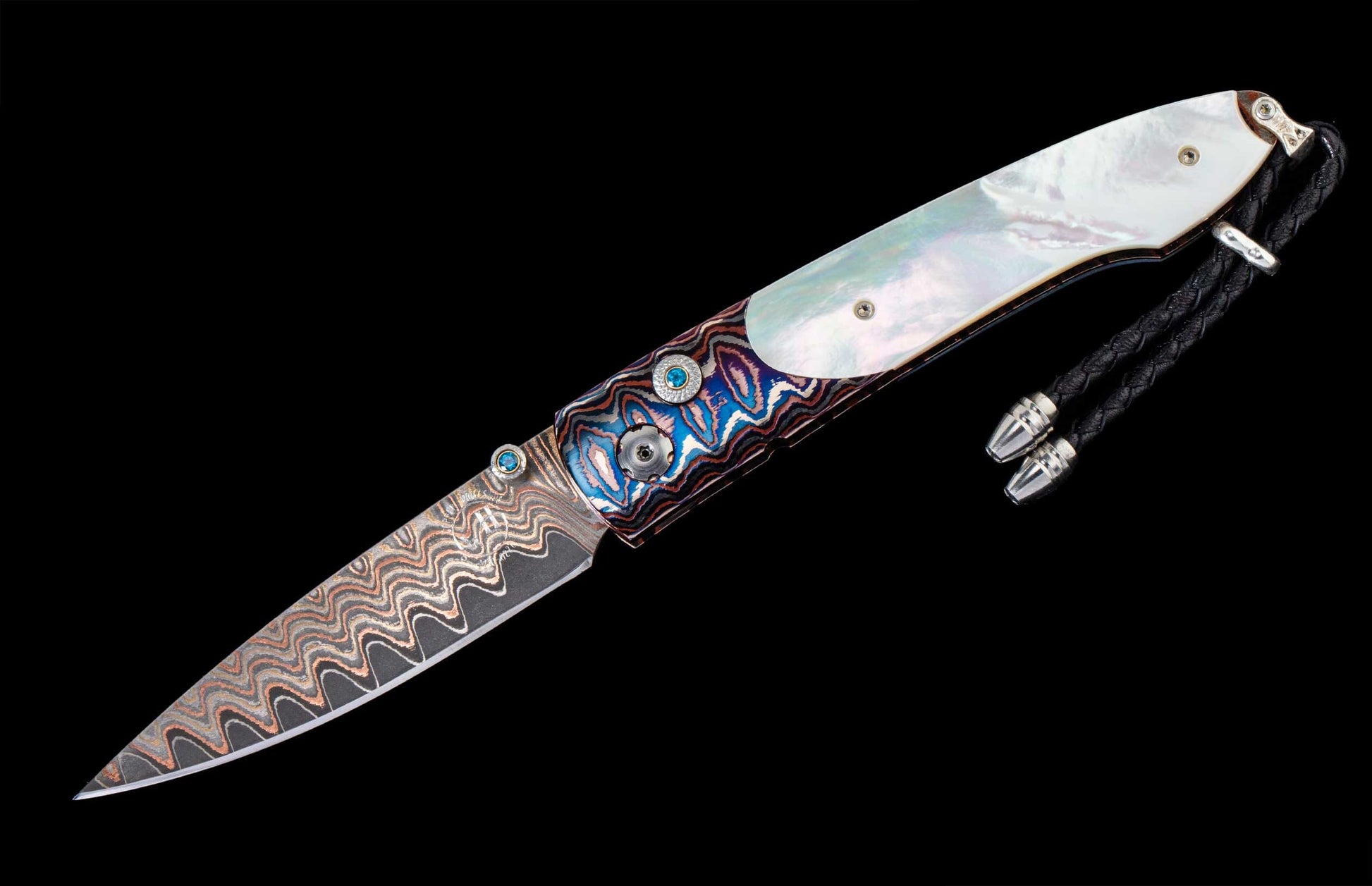 Folding knife with a wavy patterned blade, iridescent mother-of-pearl, colorful swirling handle, blue gemstones, and a braided leather lanyard.
