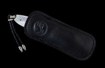 Small knife with a mother-of-pearl handle and braided black leather lanyard, partially sheathed in a black textured leather pouch with an embossed logo.