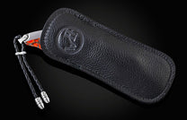 Handcrafted pocket knife from William Henry features a titanium frame inlaid with orange and red zinc matrix Apple Coral. The button lock and the thumb stud have been set with citrine gemstones and the hand forged Damascus steel blade has a copper wave pa