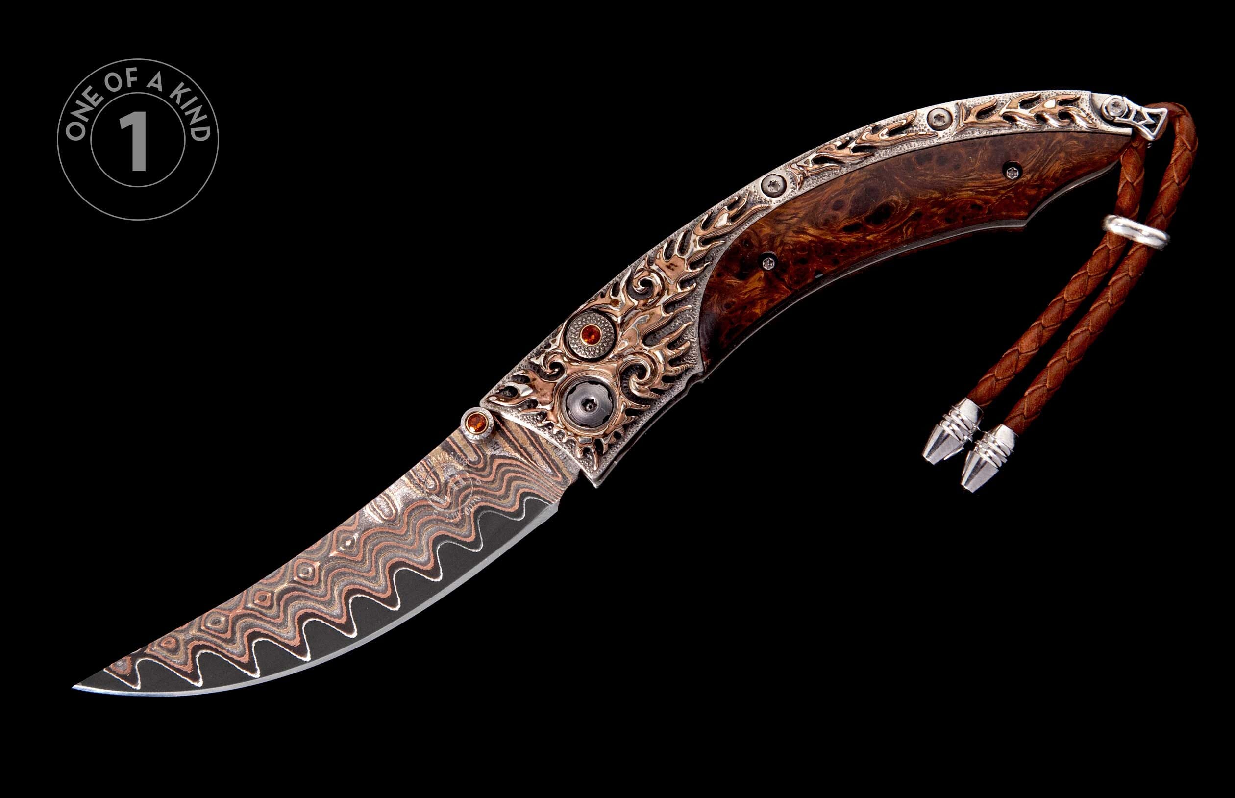 Ornate folding knife with a wavy Damascus steel blade, burl wood handle, filigree metal accents with red gems, and a brown leather lanyard.