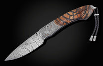 Candcrafted pocket knife from William Henry featuring hand-engraved grouse and quail with copper and 24K gold inlaid with fossil Woolly Mammoth tusk and set with spinel gem stones.. The blade is hand-forged damascus steel.